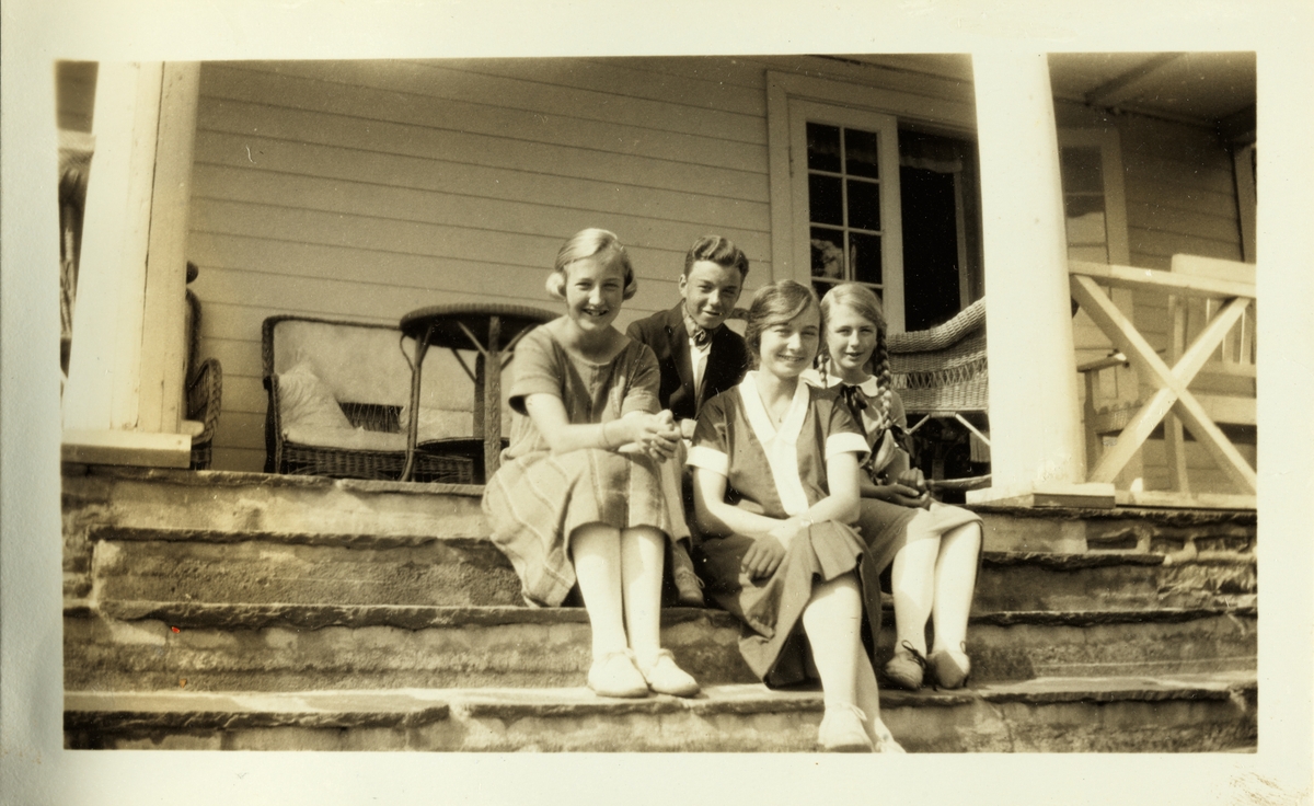 Tre unge kvinner og én mann samlet på verandatrapp i Ovnsbråten, antagelig i Asker. Fotografert sommeren 1925.