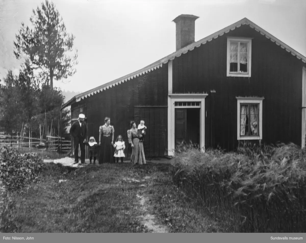 Två bilder med en man, två kvinnor och tre små barn framför gaveln på ett bostadshus med snickarglädje.