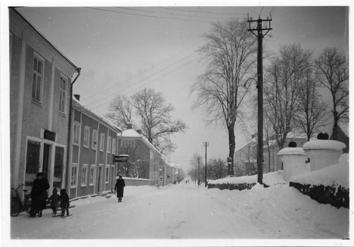 Brahegatan i Gränna i vinterskrud, mot norr. Fastigheter, bland annat "Polkagrisfabrik", till vänster och kyrkan till höger.