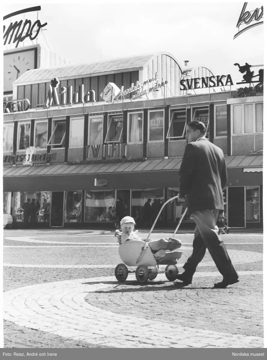 Stockholm. Vällingby centrums affärsgata. Man med barnvagn på torget utanför Twilfit.