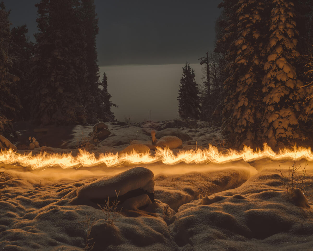 Et mørkt vinterlandskap med granskog og en lysning i midten av skogen. Horisontalt gjennom bildet løper en brennende stripe. Fotografi.