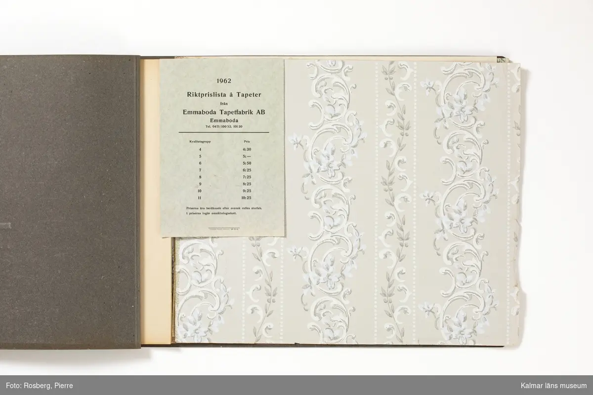 KLM 46599:4. Tapetkatalog. Katalog med pärm av grön papp eller kartong. Bunden med hjälp av tre häftklamrar. Text i silver på pärmens framsida: HILDING ADOLFSSON Enerum Tel. 01.Torp 30 BYXELKROK. Katalogen innehåller plastförstärkta tapetprover tillverkade av papper, med olika strukturer, färger och mönster, moderna under 1950 och 1960-talen. Större delen av tapetproverna saknas och endast fyra återstår, varav två av dessa ligger lösa. Inuti katalogen ett löst blad med prisuppgifter från Emmaboda Tapetfabrik AB, tryckt 1962.