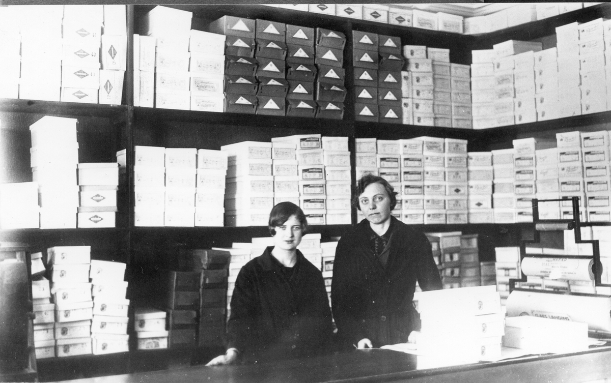 Halmstad, Fabriker: Skofabrik. Landins affär på Köpmansgatan (mitt emot tidningen Halland). På foto biträdena Ruth Gustafsson och Hulda Gustafsson. Från Brogatan flyttades affären till Köpmansgatan på 30-talet. 1941 flyttade tillverkningen till Söder och affären upphörde.