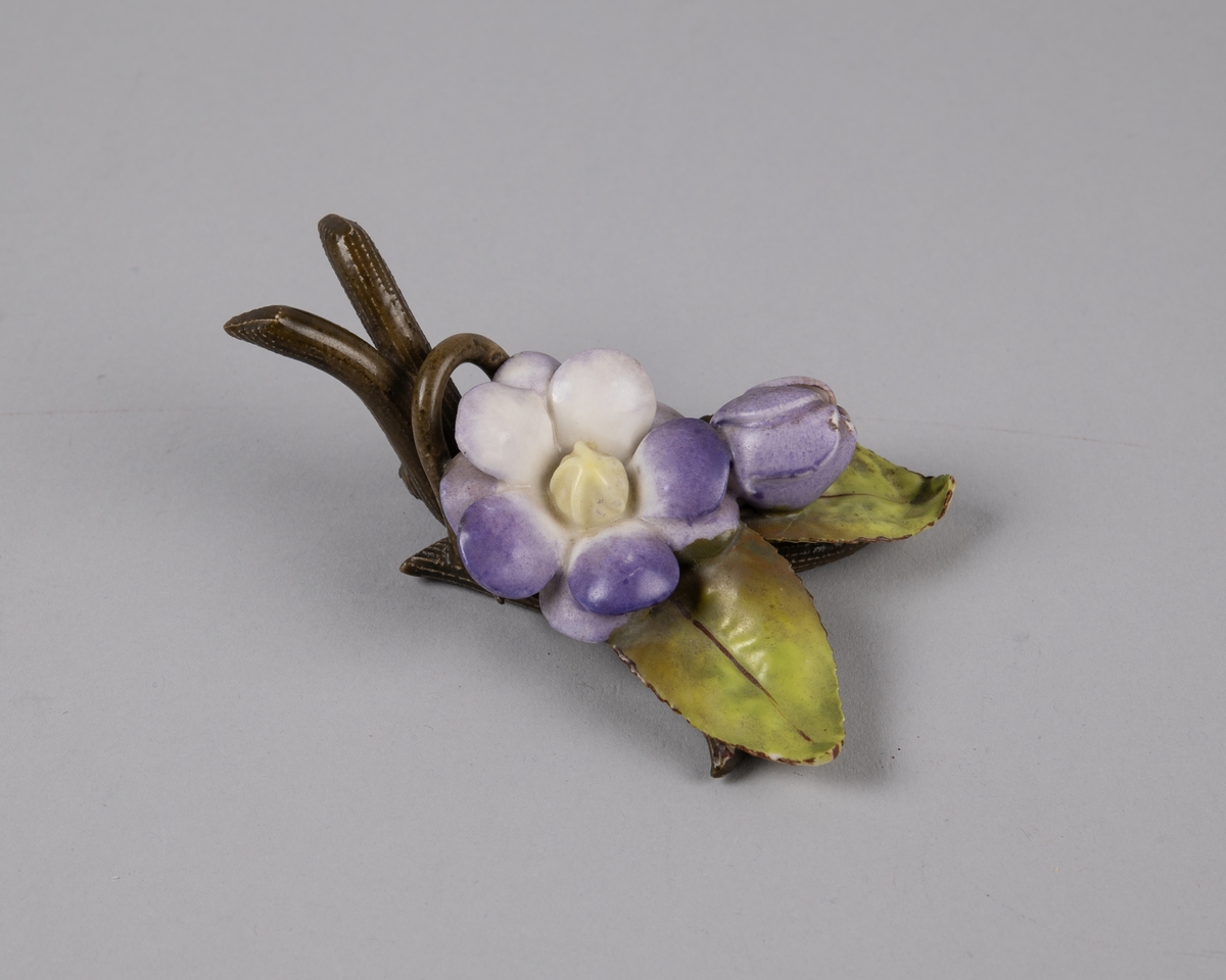 Modellert blomst med runde kronblader. Til borddekor. Stilk og grener bak danner en holder til kort eller serviett.
