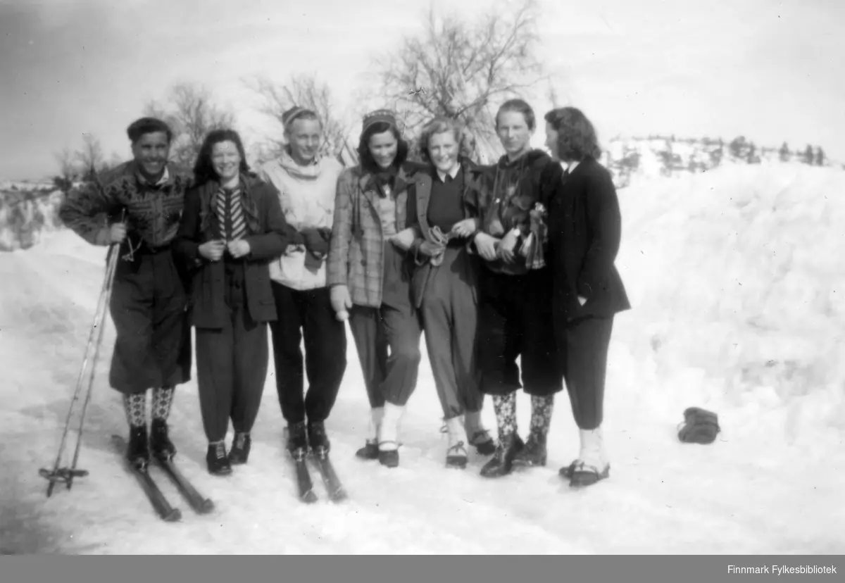 På tur til dans på Pasvik Hauk vinterstid. Fra venstre står: Terje Dahlberg, Kitty Stunes, Kolbjørn Olsen, Anne Høier, Aud Sneve, Martin Seljemo, og Bodil Pedersen. Terje  har ski på føttene. De er alle kledt i ski antrekk
