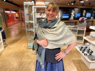 Bildet viser en dame som har kledd seg i et sjal. Sjalet har mønster fra en akvarell laget av Christiane Ritter. Sjalet selges kun hos Svalbard museum.