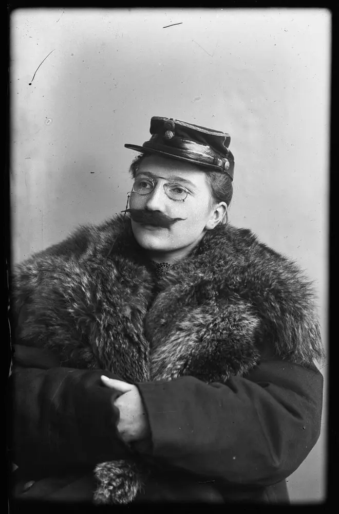 Portrait of a woman wearing a coat with a large fur collar, glasses, cap and detachable. Black and white photograph