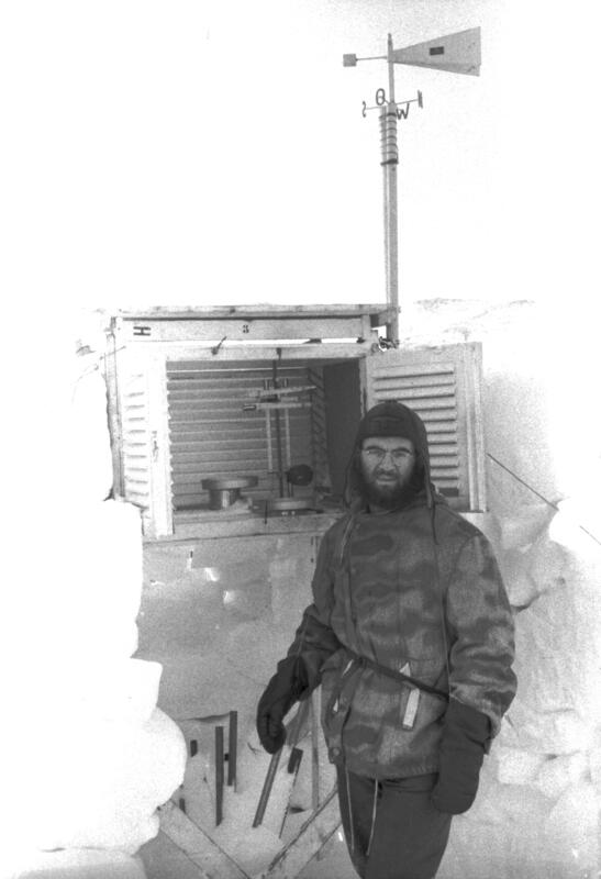 Bilde av tysk soldat foran et meteorologisk måleinstrument. Store snøskavler ved siden.