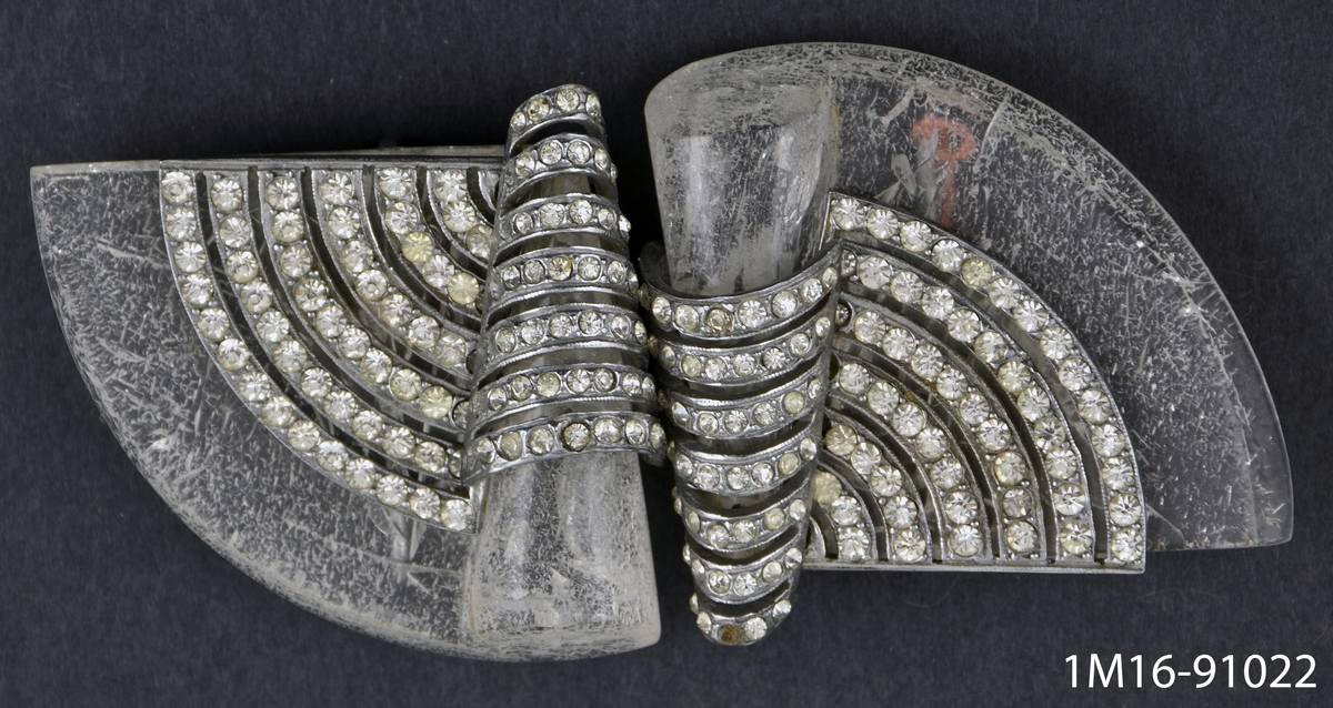 Halvcirkelformat skärpspänne av pärlbesatt metall. Två delar. Prismärkning: L.B. 26:50.