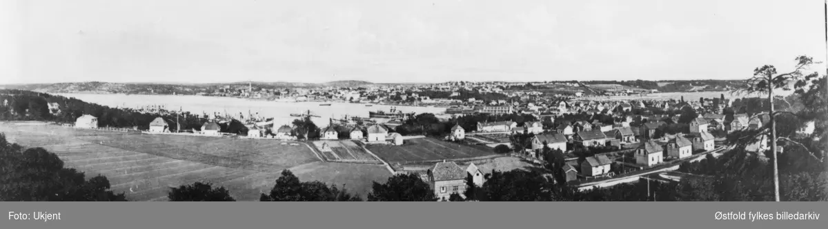 Panoramabilde av Moss by. Tatt fra Jederen, Jeløy mot øst, byen i bakgrunnen. I forgrunnen til venstre Bellevue-jordet. I forgrunnen til høyre Folke Bernadottesgate og midt i bildet Gimle gate. Ca. 1920.
