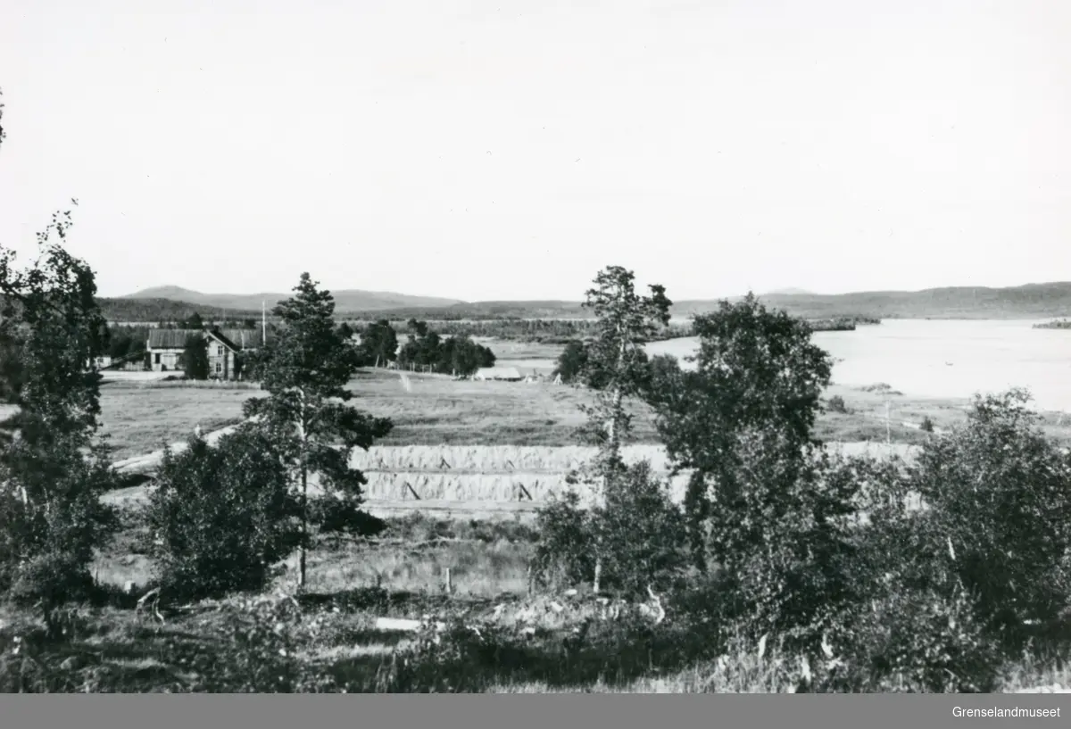 Nyrud gård i Pasvikdalen. Pasvikelven til høyre med hesjer i forgrunnen.
Bildet trolig tatt i starten av 1950 årene. 
