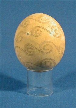 Lysegult strutseegg som står på en blank fot. Egget er dekorert med spiralformet mønster.