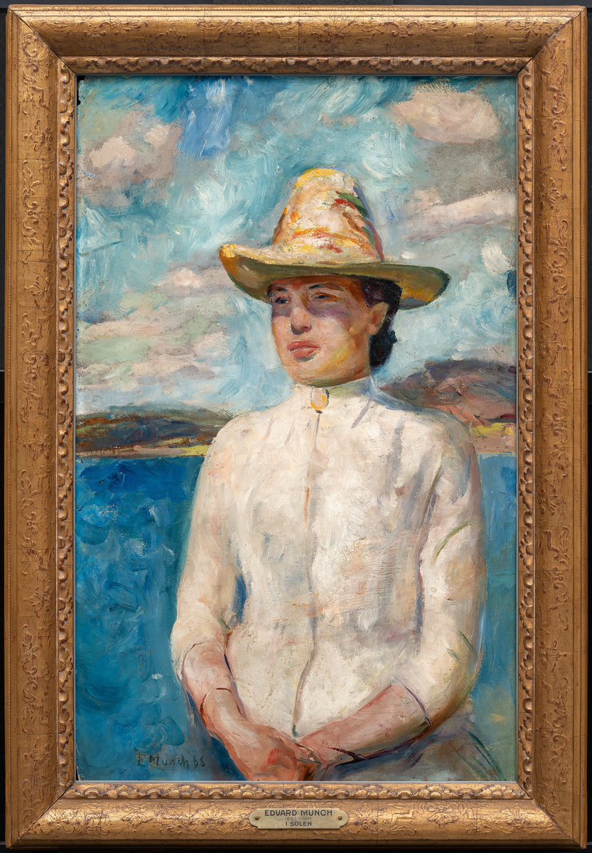 Stående ung kvinne, halvfigur en face med hodet svakt dreid mot venstre. Hvit kjole og gul stråhatt. I bakgrunnen blå sjø og lave åser. Drivende, lette sommerskyer.