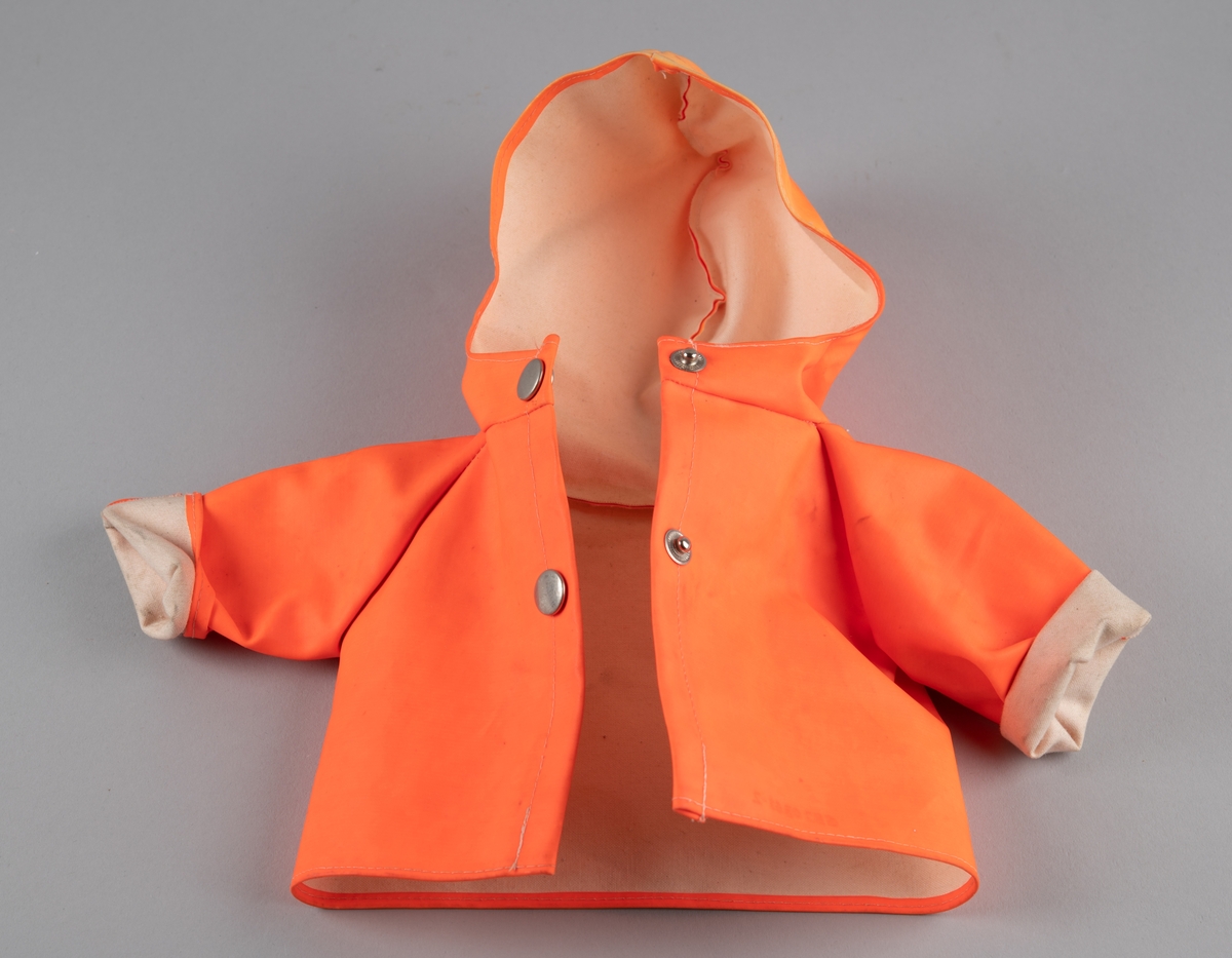 Orange regnjakke til dukke med hette og to metallknapper i åpningen foran.