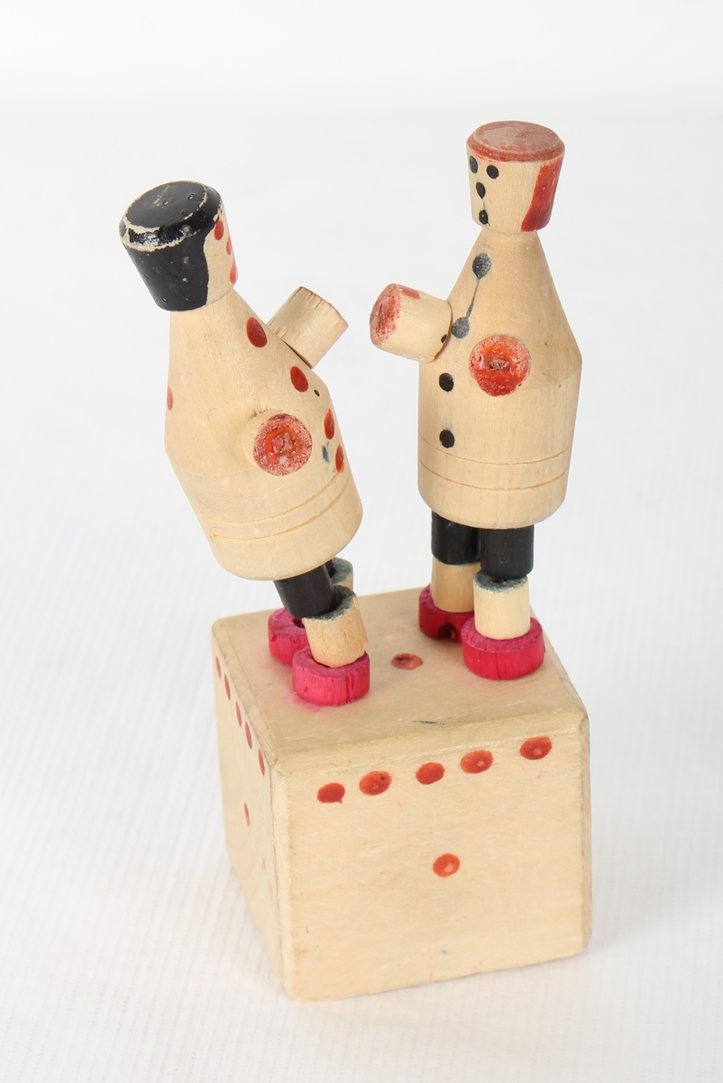 Treleike med to menneskefigurar som står på en trekloss. Figurane er ledda og har trådar inni seg som gjer at når du trykker under klossen, så rører dei på seg og ser ut som at dei boksar.