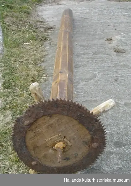 Delar till vävstol. Trä, smidda detaljer. a) Trä, metall, snidad, smidda detaljer, kugghjul i ena änden. Spännhandtag. Diameter: 28 cm, längd: 129 cm.
 b) Trä, snidad. Bredd: 10 cm, längd: 57 cm, höjd: 6 cm. 
c) Trä, snidad. Diameter: 7 cm, längd: 139 cm. 
d) Trä, snidad, profilsågad. Bredd: 7 cm, längd: 155 cm, höjd: 6 cm.
 e) Trä, snidad, den del tramorna är fästade vid. Hål för f) och vid mitten även hål i bägge ändar. Bredd: 7 cm, längd: 133 cm, höjd: 6 cm. 
f) Plugg med hål. Trä, snidad, sitter i e), samma som g). Bredd: 5 cm, längd: 18 cm, höjd: 2 cm.
g) Plugg med hål. Trä, snidad, sitter i e), samma som f). Bredd: 5 cm, längd 18 cm, höjd: 2 cm. 
h )Trä, snidad. Bredd: 5 cm, längd: 143 cm, höjd: 3 cm.
i) Trä, snidad, samma typ av föremål som b), samma funktion. Bredd: 10 cm, längd: 56 cm, höjd: 5 cm. 
j) Trä, snidad. Sittbräda till vävstol, kvadratiska hål vid kortsidorna. Bredd: 24 cm, längd: 142 cm, höjd: 2 cm. 
k) Trä, snidad, borrade hål i ena änden, den del varpen viras upp från. Diameter: 21 cm, längd: 156 cm. 
l) Trä, snidad, profilsågad, hål i bägge ändar. Bredd: 7 cm, längd: 146 cm, höjd: 3 cm.
m) Trä, snidad, sidostycke till vävstol. Bredd: 7 cm, längd: 163 cm, höjd: 143 cm. 
n) Trä, snidad, sidostycke till vävstol. Bredd: 7 cm, längd: 162 cm, höjd: 142 cm.
 o) Trä, snidad. Slagbom till vävstol. Vissa delar ersatta med nyare. Bredd: 4 cm, längd: 137 cm, höjd: 75 cm.
 p) Trä, snidad. Nytillverkad del till vävstol som ersatt en äldre. Diameter: 3 cm, längd: 147 cm.