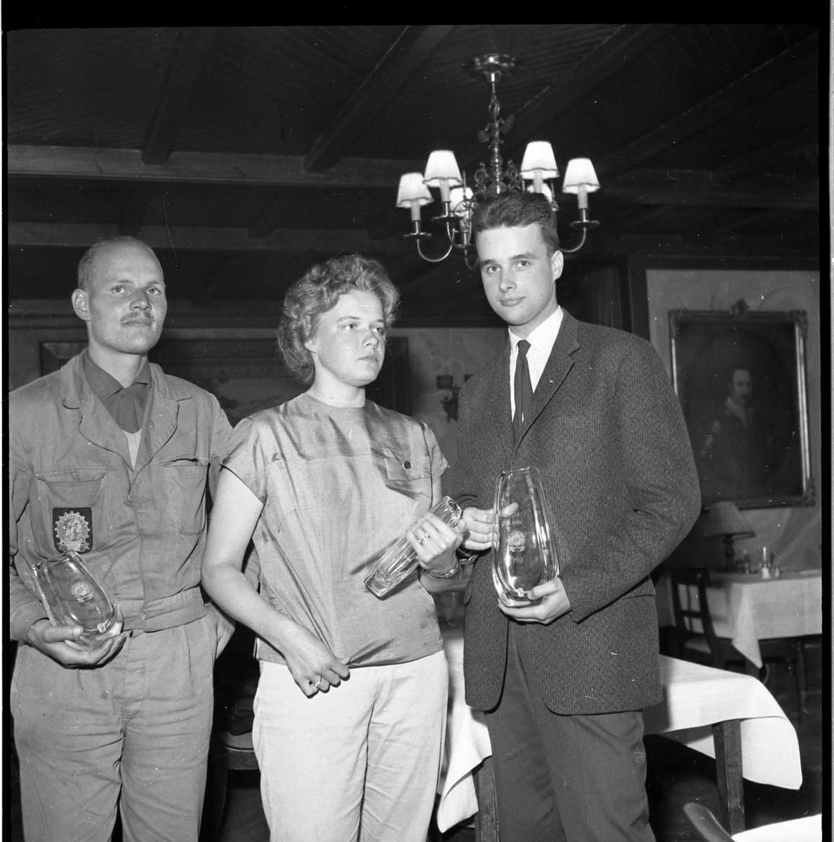 Två män och en kvinna står uppställda för fotografering. De håller i varsin glasvas med en etsning på. Eventuellt är det prisutdelning i samband med ett vesparally 1961.