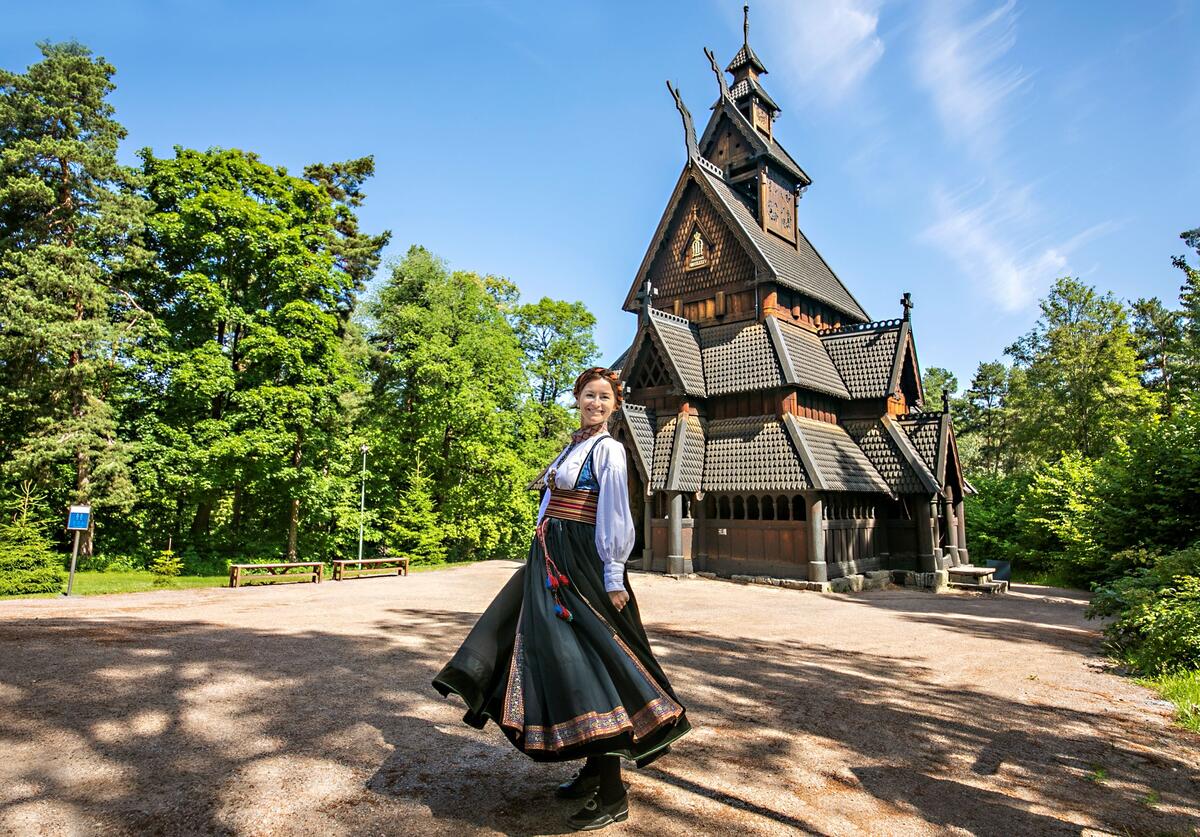 Tunvert i bunad foran stavkirken