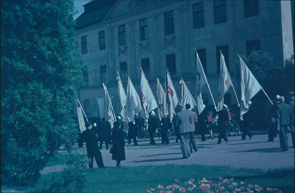 Studenter med flaggor tågar förbi Ärkebiskopsgården, Uppsala