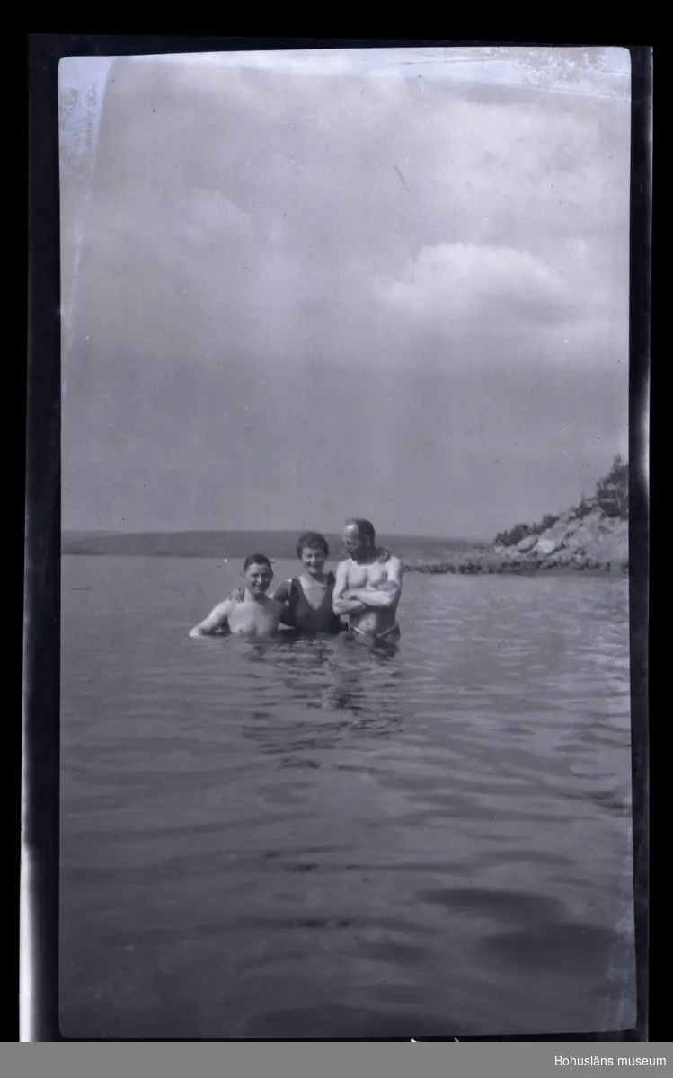 Tre personer badar i havet.