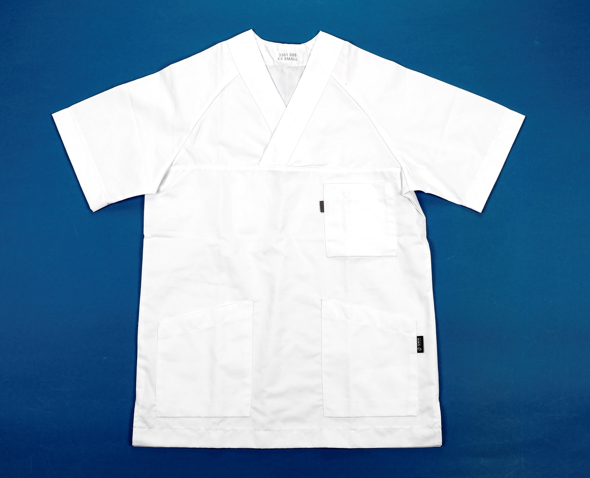 uniformsskjorte: kortermet med raglanermer. V-hals. Brystlomme og to lommer i hoftehøyde. 
