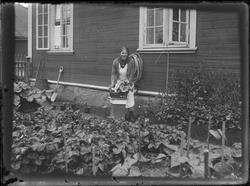Kvinne arbeider med planter i hagen foran bolighus i Rødbyen