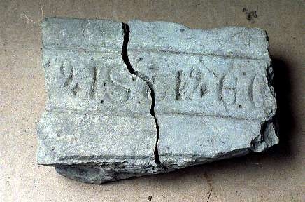 Fragment av gravhäll av kalksten, kluven i två delar. Kantskrift. Latinska bokstäver.
