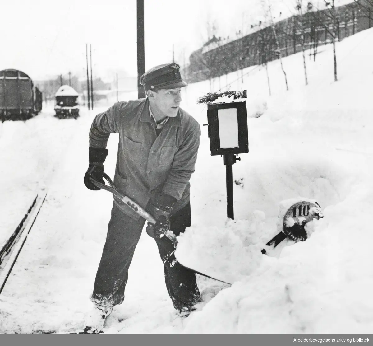 Voldsomt snøvær i Oslo. Linjevokter Johan Kjennmo i full sving med å grave ut en sporveksel ute ved Loenga i går formiddag. Det er 600 slike veksler i stasjonsområdet. Febr. 1954