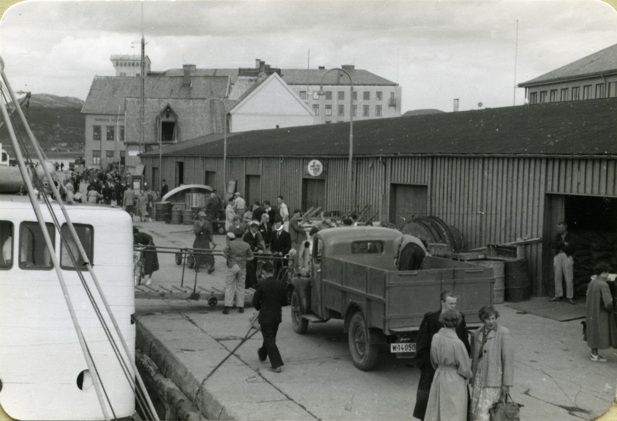 Folkeliv på kaia i Bodø tidlig på 1950-tallet; "Kaiskurene" med de ulike hurtigruteekspedisjonene. Bak ses Løvold og Chr. A. Jackhellen-bygget.