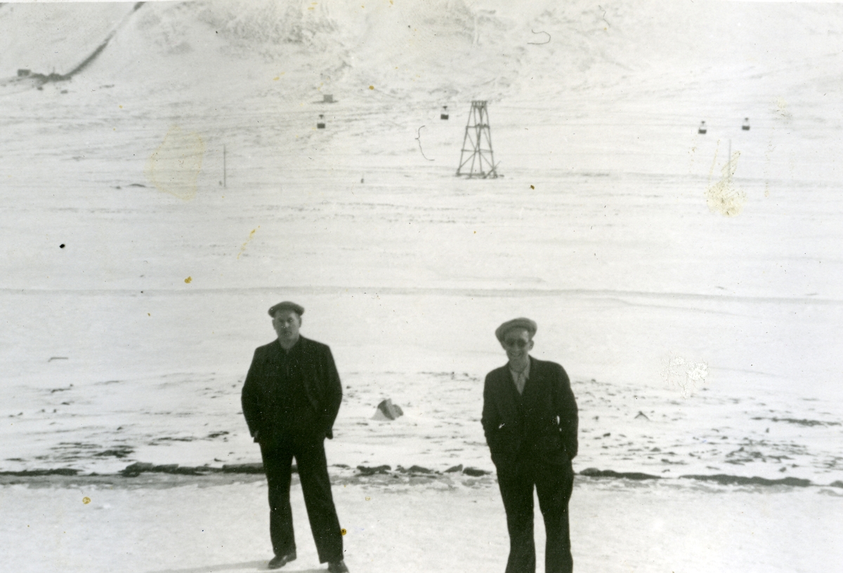 To menn på veien i Longyearbyen våren 1941. Taubanen til Gruve 2b i bakgrunnen. Bildet er tatt av Jens A. Bay, som arbeidet i gruva vinteren 1940/41.