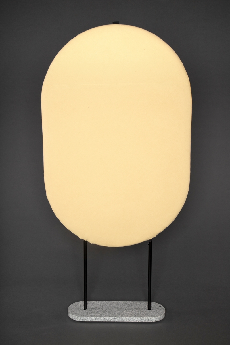 Vertikal oval romdeler i lakkert stålramme med polstret deler kledd med ullstoff, en side mørk gul og en side lys pastell gul.