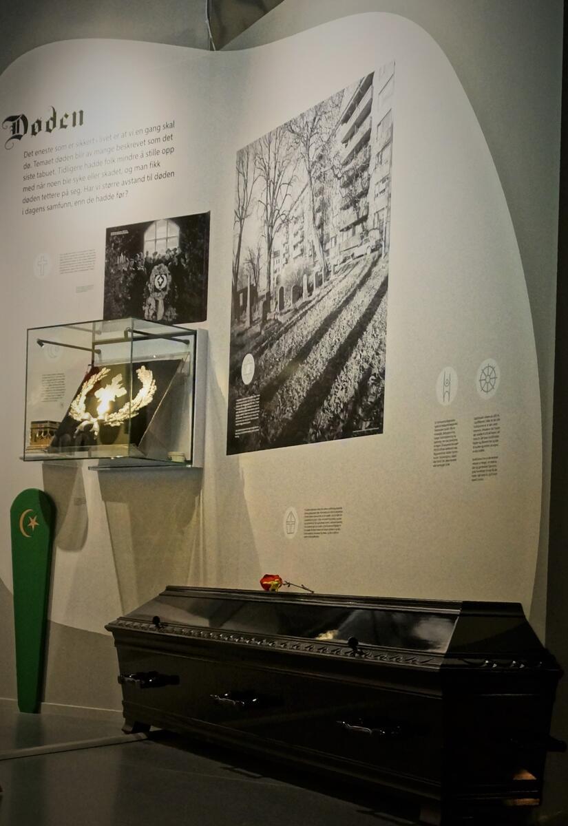 Bilde av utstillinga Fra vogge til grav. På bilde ser du en sort kiste, den jødiske gravlunden i Oslo, en begravelseskrans i sølv og en mulimsk gravmarkør