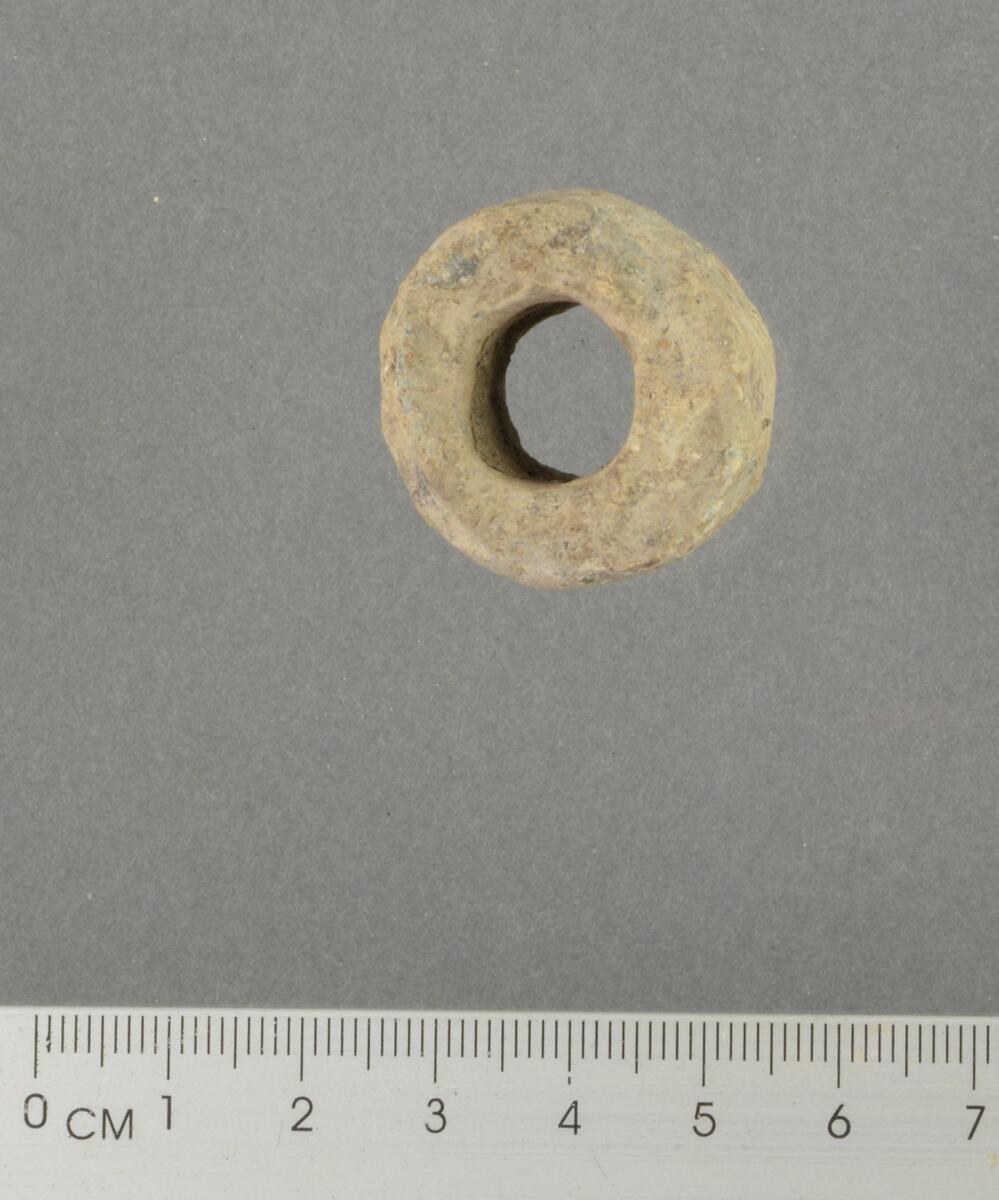 Sylindrisk spinnehjul i bly. Kan minne om Øye, (1988:49) fig, II.14 nr. 3.Spinnehjul av denne typen dateres fra slutten av 1100-tallet til tidlig 1400-tall (Øye 1988, s. 50). Mål: vekt: 79,45 g, diameter: 2,81 cm, høyde: 1,79 cm.