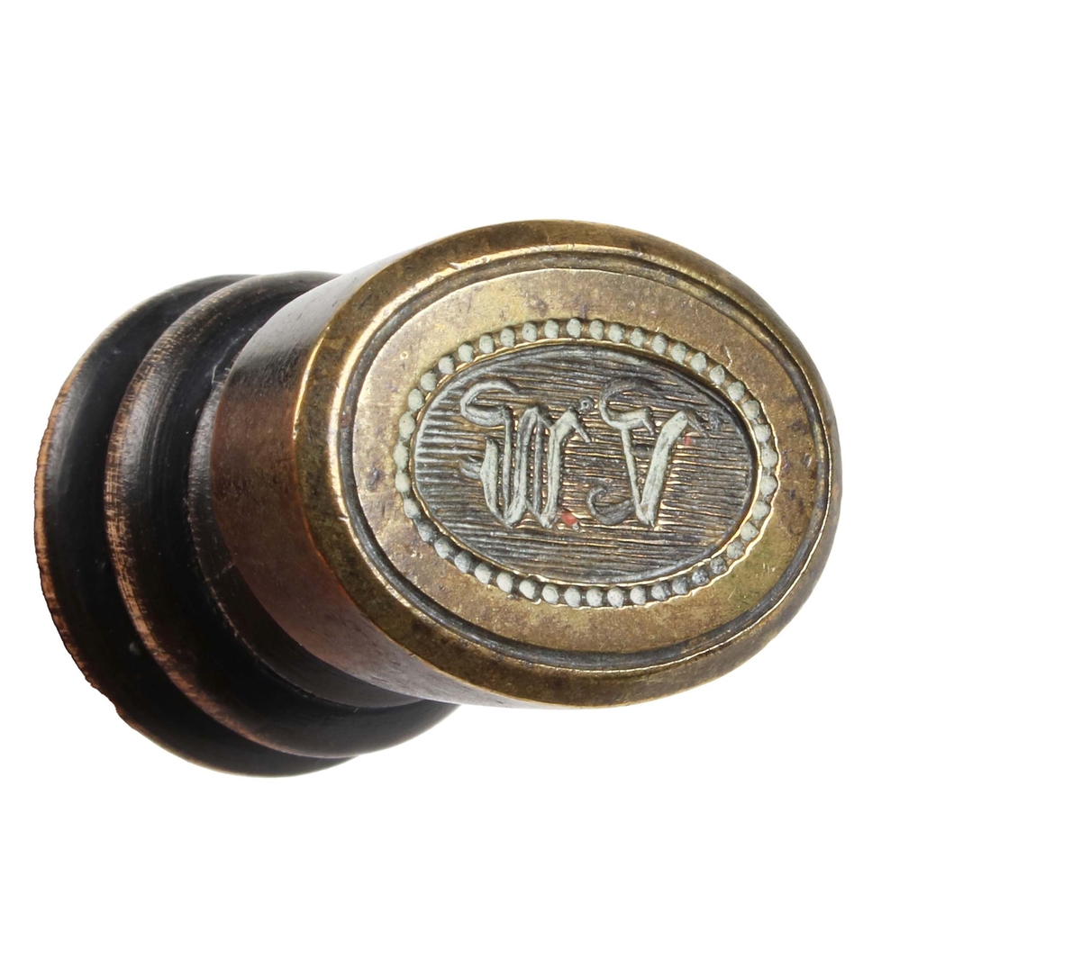 Sigillstamp. Balusterformat träskaft i svart. Oval mässingsplatta, med initialerna "V.W." mot räfflad botten, inom pärlkant.