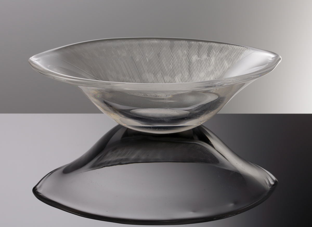 Formgiven av Edvin Öhrström. Oval skål (prov) med yttäckande slipad dekor på skålens ena sida.