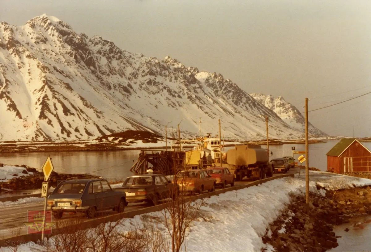 Bildet viser Lyngvær fergekai i Lofoten, med fergen "Lofotferje V" ved kai, i rute til Smorten på Vestvågøy.  
Bildet er tatt mellom 1977 og 1979. 
Denne fergen ble innkjøpt til Lofoten Trafikklag fra MRF i mai 1977. Med tanke på at en ikke skimter bygging av Gimsøystraumen bro i bakgrunnen, antas bildet å være datert mellom 1977 og 1979. 

Ref. til bilde NVM 18-F-02361 SCN2.