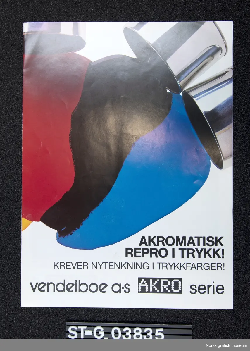 En folder for Vendelboes akromatiske farger. 
Forsiden viser rød, sort og blå farge som flyter utover, og innsiden demonstrerer den nye trykksverten ved å gjengi det samme fotografiet med ulikt trykk.