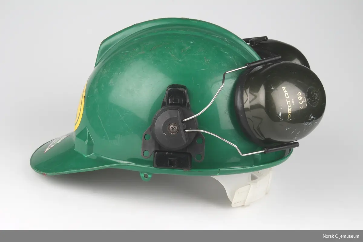 Grønn vernehjelm med hørselsvern. Foran på hjelmen er det et klistremerke med logo til Flopetrol Johnston Schlumberger.
