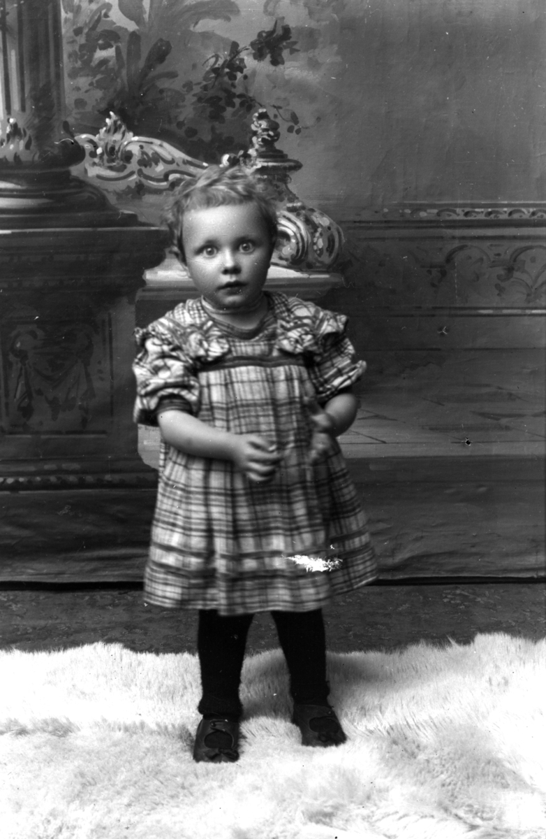 Atelierfoto.Et barn, ei liten jente i kjole.
