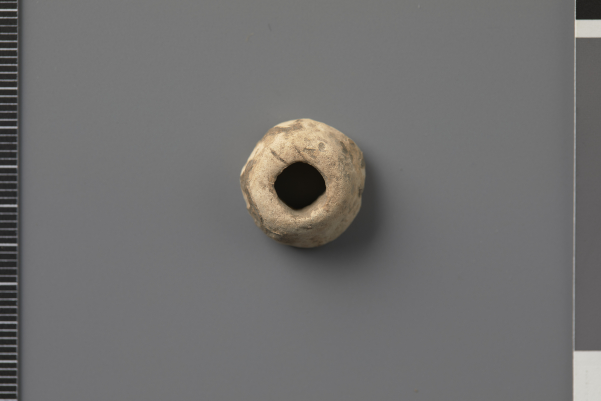 Spinnehjul av bly. Tilnærmet konisk med flat topp. Form som Øye type C og Høigård Hofseth type IA/IIG.  Diam. 1,6 cm, h. 0,8 cm, hulldiam. 0,7 cm. Vekt 9,7 g.