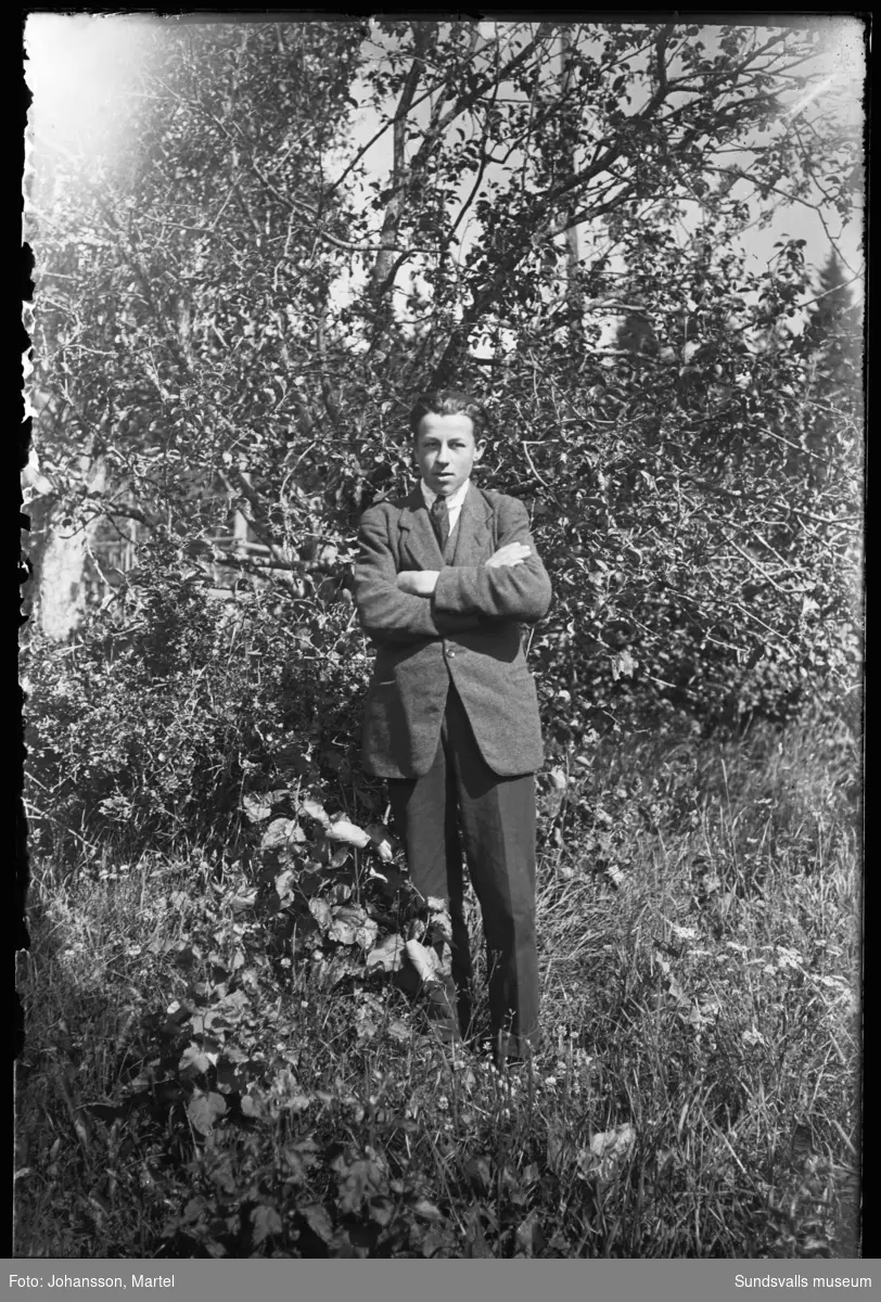 Porträttbild av en ung man ute i en trädgård.