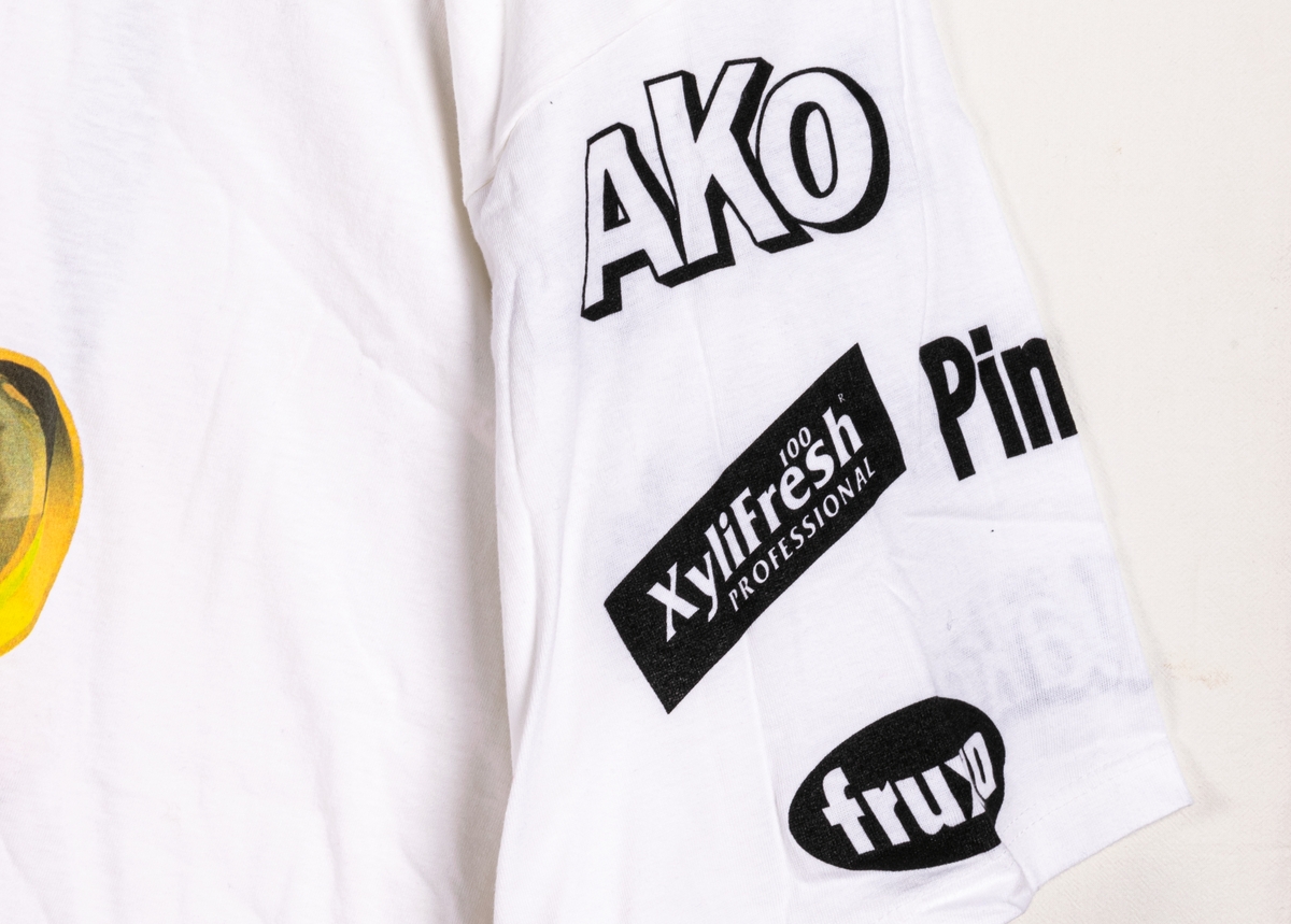 Reklamtröja, vit t-shirt med tryckt bild av en stiliserad sjörövare på fram- och baksida. På ärmarna syns logotyper för olika tablettprodukter från Ahlgrens sortiment.