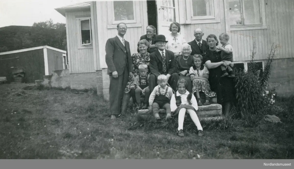 Familie sittende på en trapp. Det eldre ekteparet midt i bildet er Anton Jørgen Zahl (f. 1869) og Mathilde Ingardine Zahl (f. 1967). De øvrige er barn, svigerbarn og barnebarn. Familien kom fra Brønnøy, og Anton var fyrvokter på Flatøy fyr i tidsrommet 1920-1939.