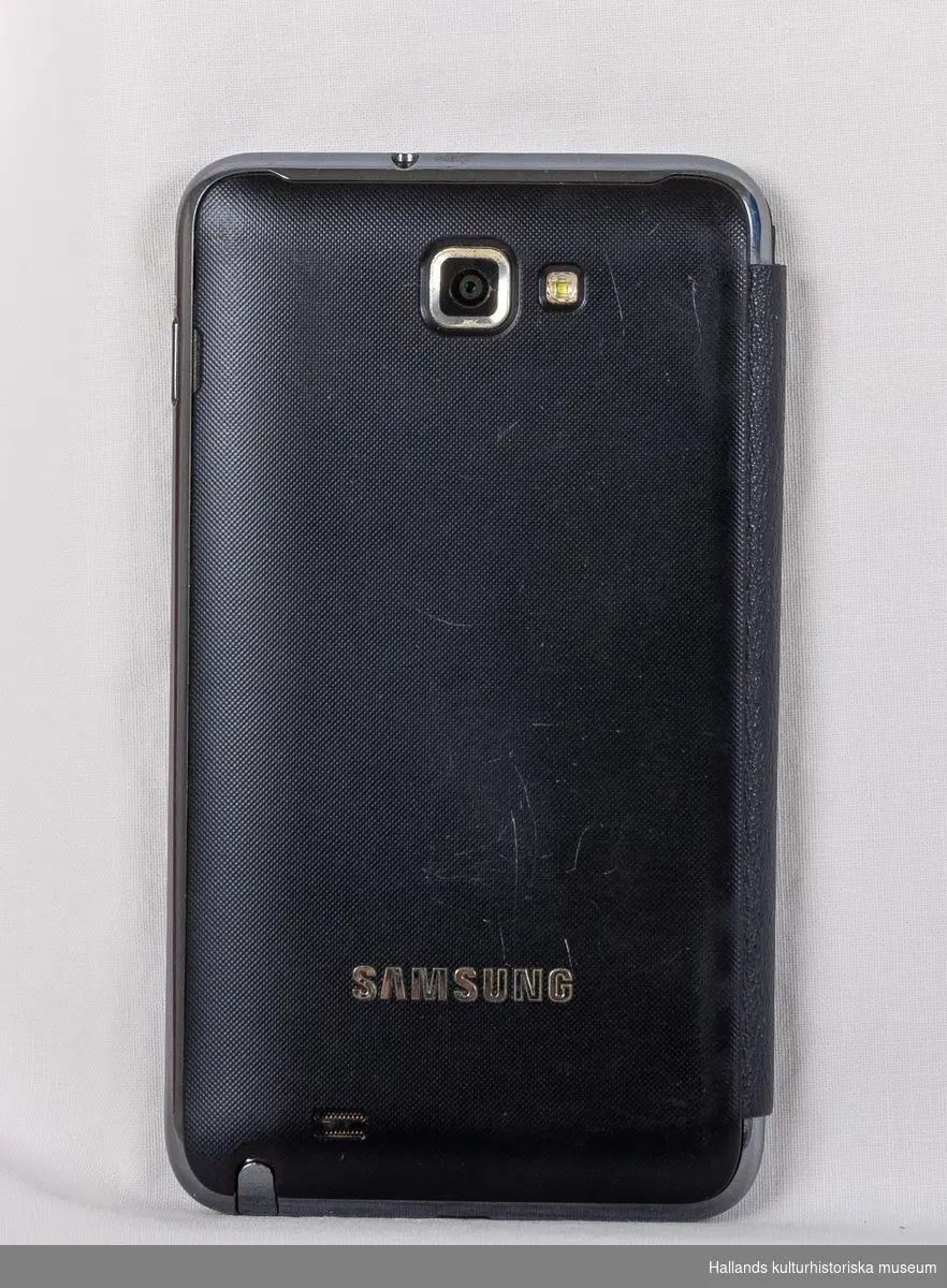 Samsung Galaxy Note (Tillverkare: Samsung, modell: Galaxy Note) med yttre skal av svart hårdplast och metall. Telefonen har ett vikbart fodral av svart konstläder.

På telefonens framsida en digital skärm med sensor för tryck, en tryckknapp, högtalare, kameraoptik, samt en märkning: Samsung. På telefonens baksida kameraoptik, en lysdiod för blixtljus, samt en märkning: Samsung. Baksidan går att knäppa loss för åtkomst av batteri och telefonkort (sim). I telefonen sitter ett simkort från teleoperatören Telia.