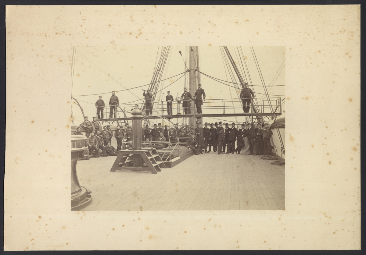 Bilden visar sjöofficerare och manskapet som har tagit uppställning på däck av fregatten Vanadis för fotografering år 1868.