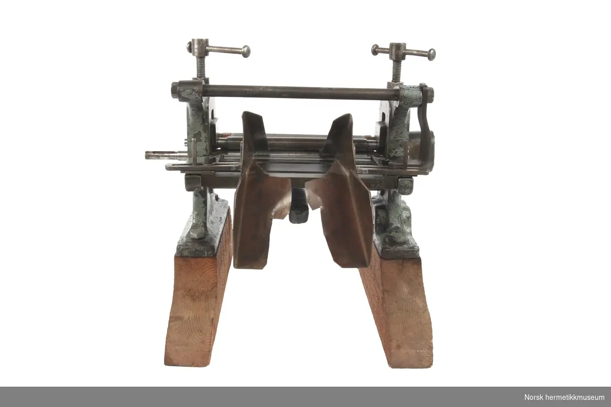 Liten valsemaskin i stål montert på to treføtter. Produsert av Erdmann Kircheis, Sachsen, Tyskland.
