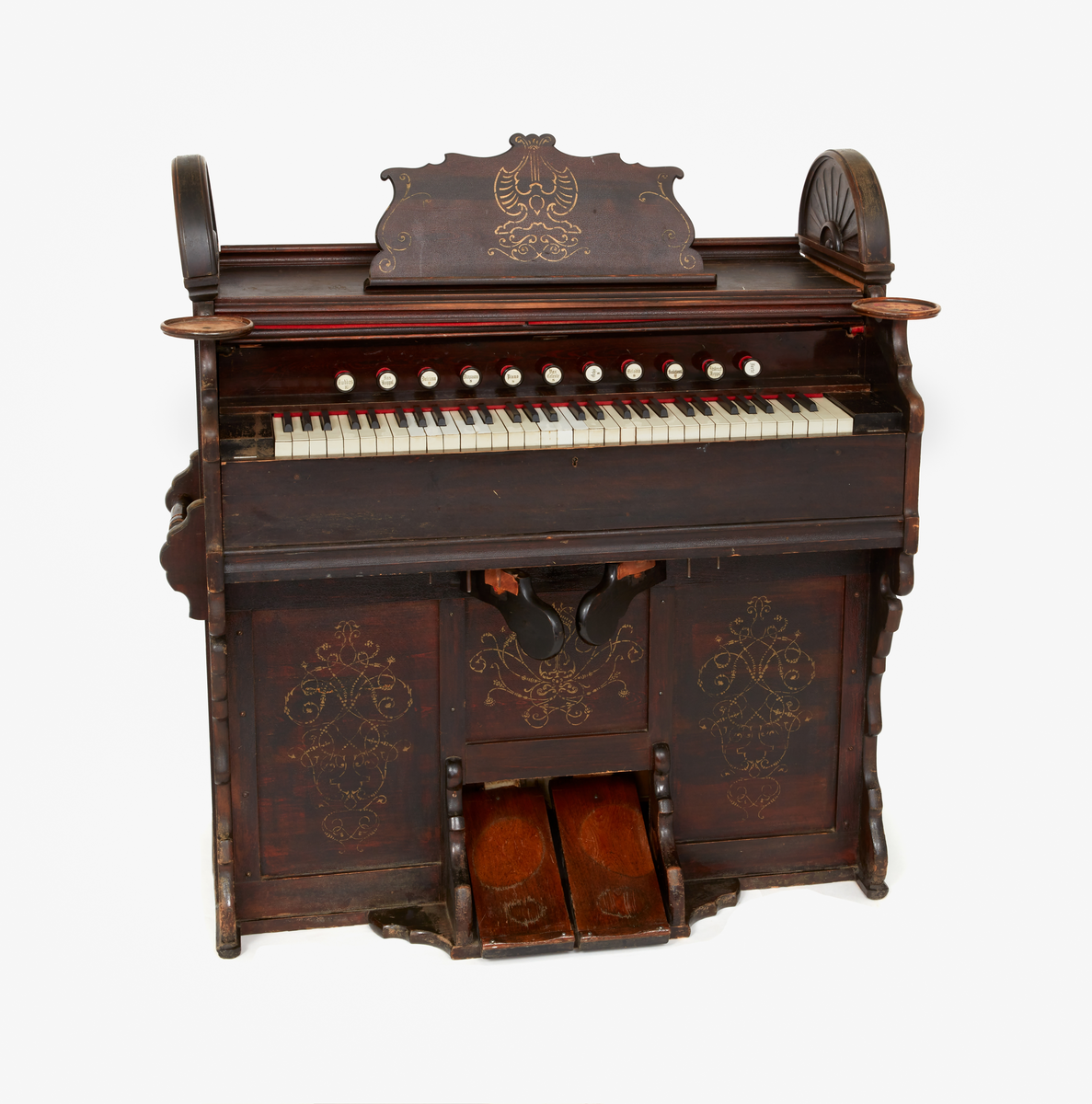 Orgelharmonium i brunbetsat trä. 
11 registerandrag. 5 oktaver.
Påmålad ornamentik i guldfärg. 
Hållare för ljusstakar på varje sida.
2 lösa halvmåneformade gavelornament.
Sannolikt tillverkat i början av 1900-talet.