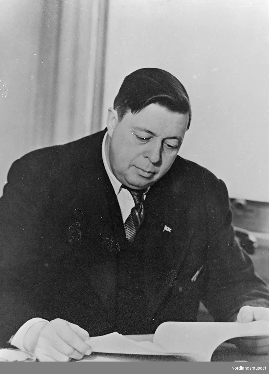 Bildet viser en mann, Leif Jensson, som sitter ved et bord og leser.