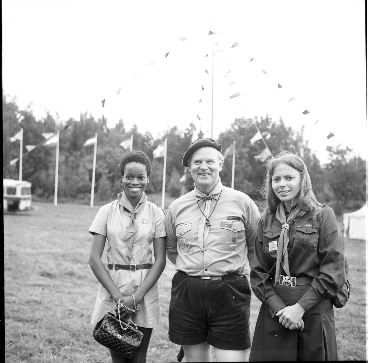 En man i Frälsningarméns scoutklädsel står mellan två unga kvinnor.