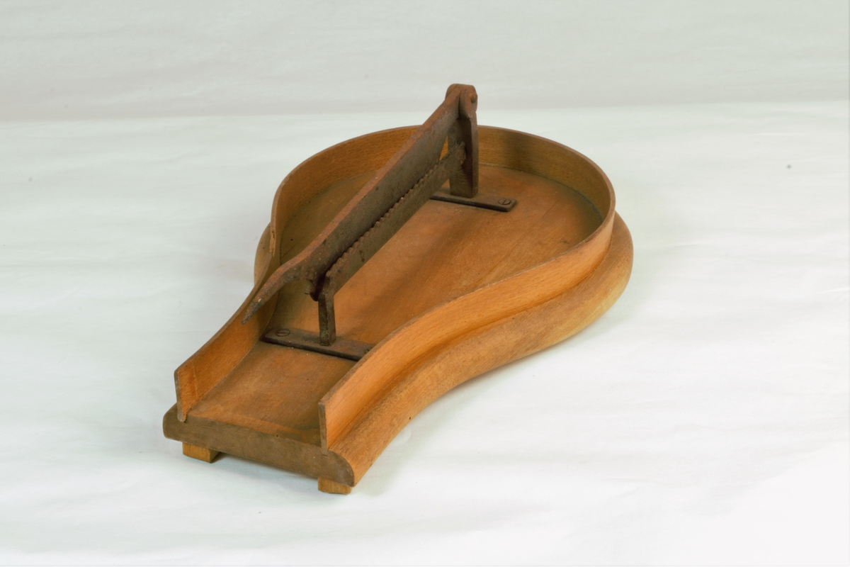 Violinformet trebrett med sidekanter, påmontert en saks av jern. Håndtak mangler.